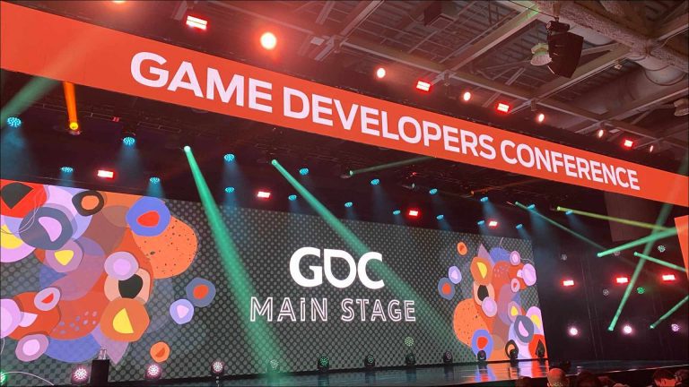 The main stage at the GDC Event is illuminated with vibrant lights and decorated with colorful graphics, showcasing the event's focus on the gaming industry.