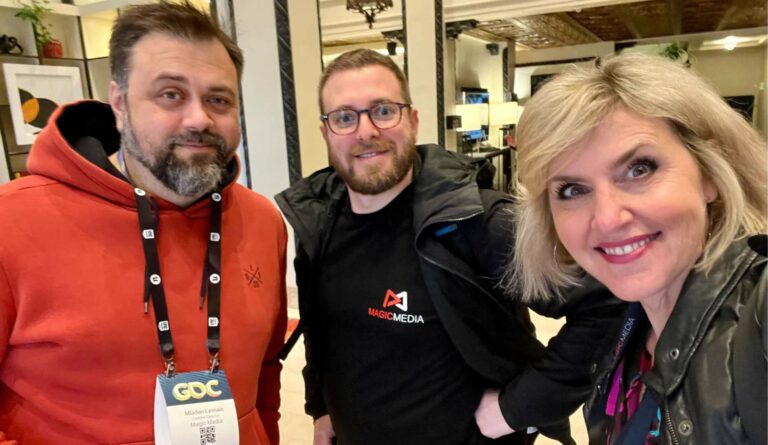 Magic Media team members smiling at GDC 2024, with one person wearing a branded jacket.